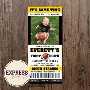 May include: A yellow and black football-themed first birthday party invitation with a photo of a baby boy holding a football. The invitation says "It's Game Time! Our little boy is turning one!" and "Please join us for Everett's First Down. Saturday, October 5. Kick Off - 11:00 a.m. Concession stand opens at half-time. Smith Stadium. Optional attire - favorite sports team. Sec 10, Row 05, Seat 19."