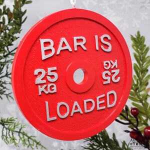 May include: Red Christmas bauble shaped like a weight plate with the text "BAR IS LOADED" and "25 KG" in silver lettering.