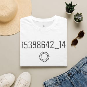 Könnte beinhalten: Ein weißes kurzärmeliges T-Shirt mit dem dunkelgrauen Aufdruck 15398642_14 auf der Brust, einer kleinen kreisförmigen Grafik aus Strichen direkt unter den Zahlen und einem winzigen kreisförmigen Symbol in der Nähe des Halsausschnitts.