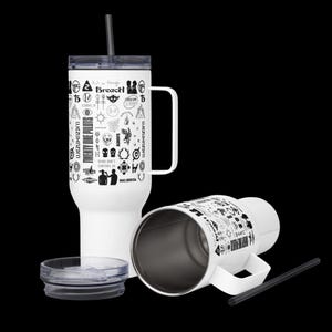 May include: White tumbler with a black straw, handle, and lid. The tumbler features a variety of black graphic designs and the text "Twenty One Pilots". The lid is off, and another tumbler is lying on its side.