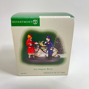 May include: A Department 56 Christmas in the City series figurine. The box features a scene with a woman in a red coat and a mail carrier in a blue uniform next to a bicycle. The text "Your Telegram, Ma'am" is visible.