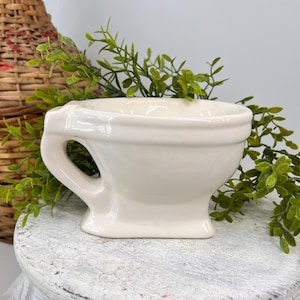 May include: A set of three ceramic mugs with a speckled, matte finish. The mugs are in shades of cream, light gray, and dark gray. Each mug has a simple, minimalist design, perfect for coffee or tea.