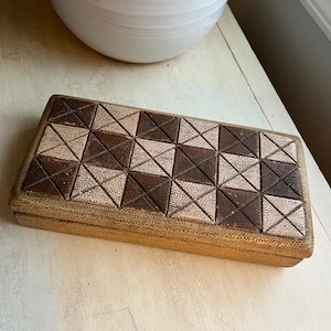 May include: A rectangular box with a geometric pattern of brown and beige squares and triangles. The box is made of a textured material and has a gold-colored finish.