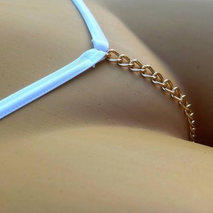 Könnte beinhalten: Weiße Dessous mit goldenem Kettendetail.