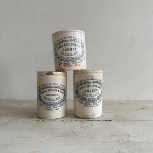 May include: Three antique James Keiller & Sons Dundee Marmalade jars. The jars are cylindrical, cream-colored, and feature black text and a decorative border. The text includes "Prize Medal for Marmalade, London, 1862."