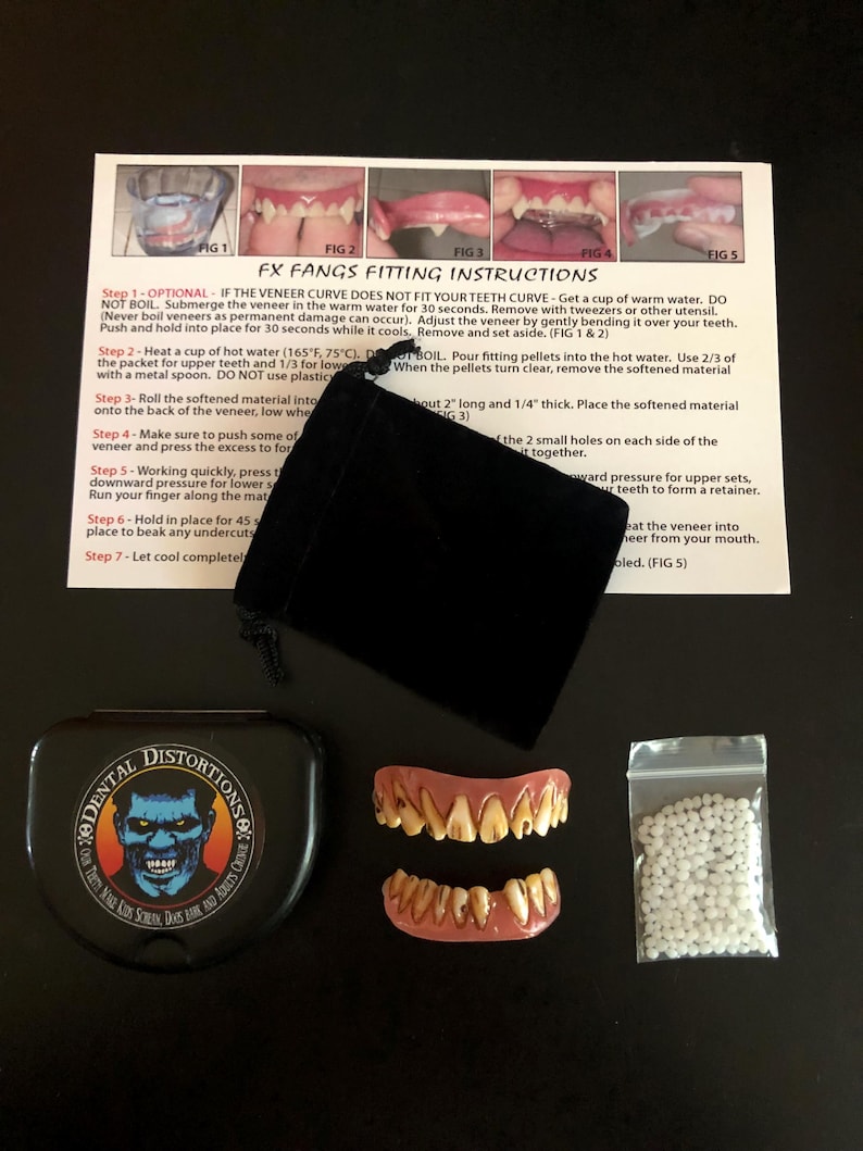 Op de afbeelding: Een set vampierstanden in een zwarte doos met een zakje witte korrels en instructies over hoe ze te passen. De instructies bevatten de tekst "FX Fangs Fitting Instructions".