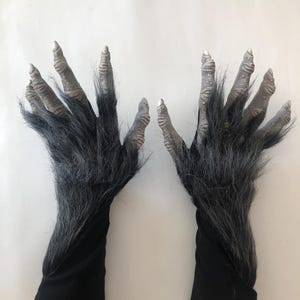 Op de afbeelding: Een paar zwarte weerwolfkostuumhandschoenen met grijze klauwen en zwart bont.