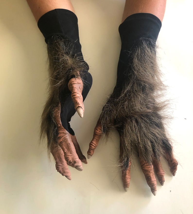 May include: A pair of black and brown werewolf costume gloves with furry details. The gloves have long, clawed fingers.