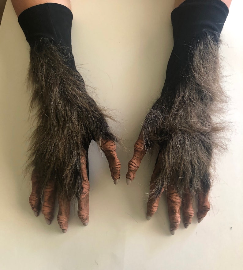 May include: A pair of brown furry werewolf costume gloves with black fabric cuffs. The gloves have detailed, clawed hands.
