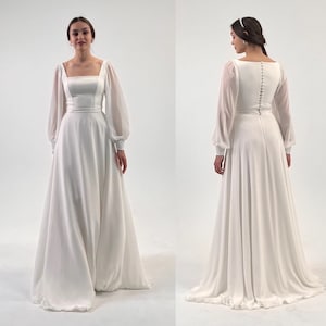 Puede incluir: Un vestido de novia blanco con escote cuadrado y mangas largas transparentes. El vestido presenta un corpi&ntilde;o ajustado y una falda fluida. La parte trasera del vestido tiene una fila de botones. La modelo lleva una diadema blanca.