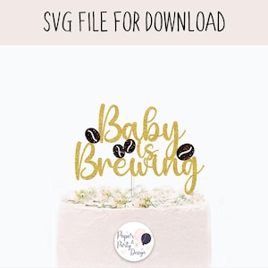 May include: A gold glitter cake topper with the words "Baby is Brewing" and coffee bean accents. The topper is on a white cake, with the text "SVG FILE FOR DOWNLOAD" at the top.