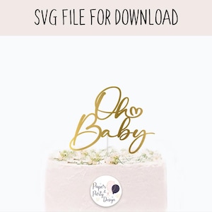 Puede incluir: Un adorno dorado para pastel con la frase "Oh Baby" en cursiva. El adorno está colocado sobre un pastel blanco decorado con pequeñas flores blancas. El texto "SVG FILE FOR DOWNLOAD" está en la parte superior.