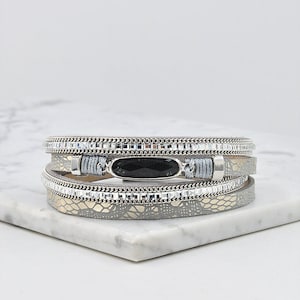 May include: A gray leather wrap bracelet with a black stone accent and silver chain detail.
