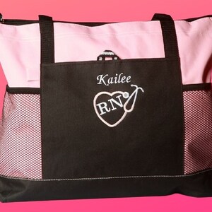 Peut inclure: Un sac fourre-tout noir et rose avec une poche en filet. Le sac a un c&oelig;ur avec les lettres "RN" &agrave; l'int&eacute;rieur et un st&eacute;thoscope. Le sac est personnalis&eacute; avec le nom "Kailee".