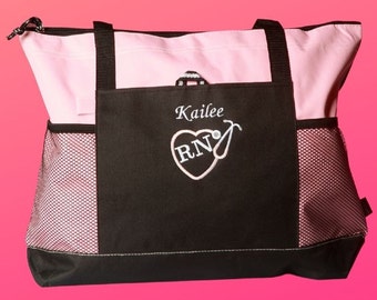 Peut inclure: Un sac fourre-tout noir et rose avec une poche en filet. Le sac est personnalisé avec un motif brodé avec le nom "Kailee" et un cœur avec "RN" et un stéthoscope.