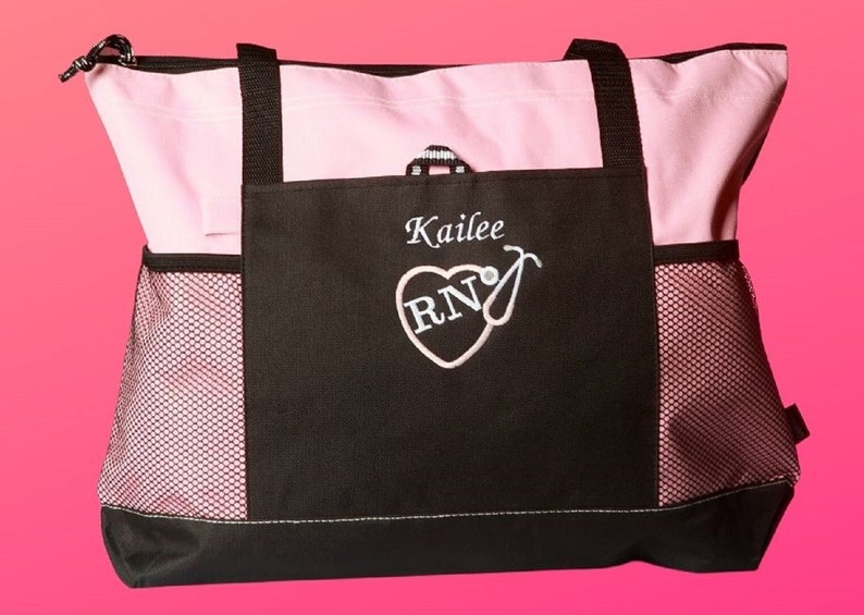 Peut inclure: Un sac fourre-tout noir et rose avec une poche en filet. Le sac a un c&oelig;ur avec les lettres "RN" &agrave; l'int&eacute;rieur et un st&eacute;thoscope. Le sac est personnalis&eacute; avec le nom "Kailee".