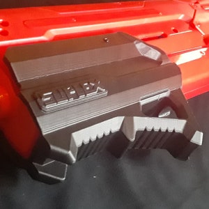 Può includere: Una pistola giocattolo rossa e nera con un'impugnatura nera e la parola "REMARK" stampata su di essa.