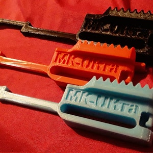May include: Three 3D printed keys in black, orange, and light blue. Each key has a gear-like design on one end and the text "MK-Ultra" printed on the other end.