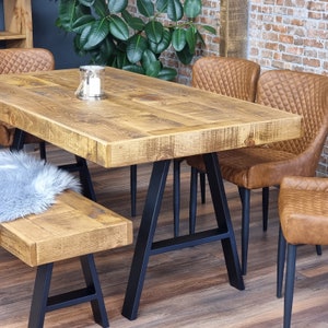 May include: A rustic wooden dining table with black metal legs and a matching bench. The table has a distressed finish and is surrounded by brown leather chairs.