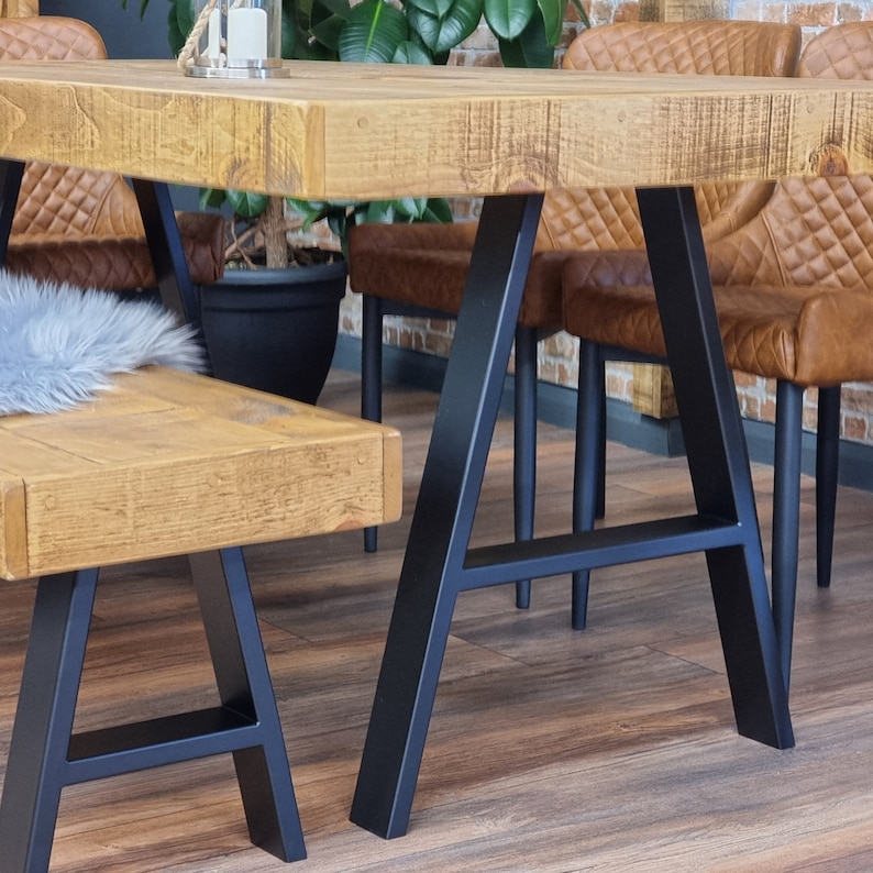 May include: A wooden table with a black metal A-frame base. The table has a rustic, distressed finish and is paired with a matching bench.