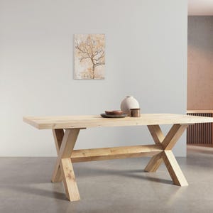 May include: A light wood dining table with a rectangular top and a unique X-shaped base. The table has a lower shelf for storage.