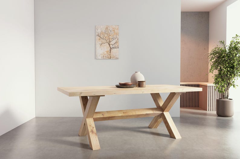 May include: A light wood dining table with a rectangular top and a unique X-shaped base. The table has a lower shelf for storage.