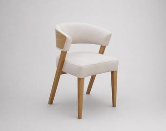 May include: A dining chair featuring a light cream upholstered seat and curved backrest. The frame is constructed from light-toned wood, with the backrest sides accented by matching wooden panels that connect to the four tapered wooden legs.