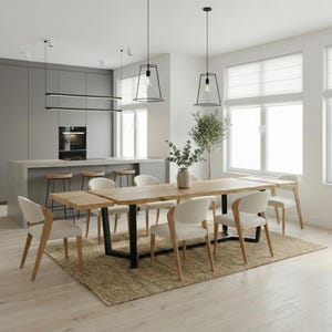 May include: A contemporary dining space with a large wooden table on a black metal frame, complemented by white chairs. The room features a neutral rug, pendant lights, and a kitchen island with bar stools. The table is approximately 240cm long.