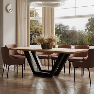 May include: A modern dining table with a wooden top and black metal legs in a V-shape. The table is surrounded by six chairs with brown upholstery.