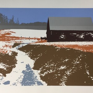 May include: A black barn with a gray roof stands in a snowy field with a stream running through it. The sky is blue and the field is covered in snow with patches of brown and orange.