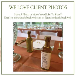 May include: Two small olive oil bottles with gold caps are displayed on a table. One bottle has a label that reads "Thank you for showering Jennifer with Olive the Love." The text "WE LOVE CLIENT PHOTOS" is at the top of the image.