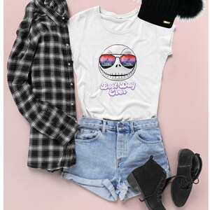 K&ouml;nnte beinhalten: Wei&szlig;es T-Shirt mit einem Grafikdruck von Jack Skellington, der eine Sonnenbrille mit einem Stadtbild-Reflex tr&auml;gt. Der Text "Best Day Ever" ist in Lila unter dem Grafikdruck gedruckt. Das T-Shirt wird mit Jeans-Shorts, einem schwarz-wei&szlig; karierten Hemd und schwarzen Stiefeln kombiniert.