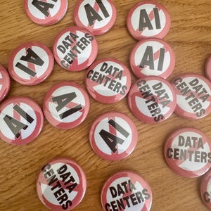 May include: A collection of round pin-back buttons featuring a white background with a red circular border and a red diagonal slash. Some buttons display the black text AI, while others feature the black text DATA CENTERS.
