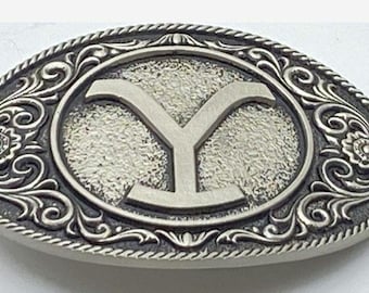 Fibbia per cintura Yellowstone con motivi western a volute, dettagli floreali e bordo a corda intrecciata.