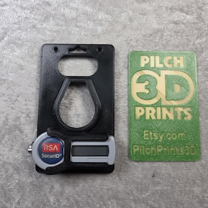 May include: Black 3D-printed security token holder with a slot for a digital display and a key fob. Includes a green card with gold text that reads "PILCH 3D PRINTS" and "Etsy.com PilchPrints3D".