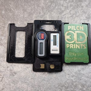 May include: Black 3D-printed holders for security devices. The holders contain a security token, a digital display device, and a USB drive. One holder has the text "PILCH 3D PRINTS" and "Etsy.com PilohPrints3D".