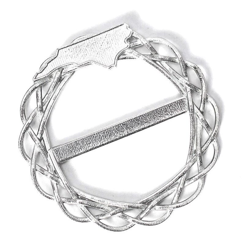 May include: Silver-toned metal belt buckle featuring a raised outline of the state of North Carolina. The buckle is circular with a woven design and a straight bar across the center.