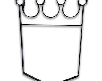 Può includere: Cornice in metallo nero a forma di corona con base esagonale. La cornice è vuota e pronta per essere riempita con una foto o altro elemento decorativo.