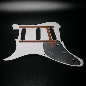 Pu&ograve; includere: Corpo di chitarra elettrica bianco con nastro di rame e un battipenna nero. Il corpo &egrave; in legno e ha una forma classica.