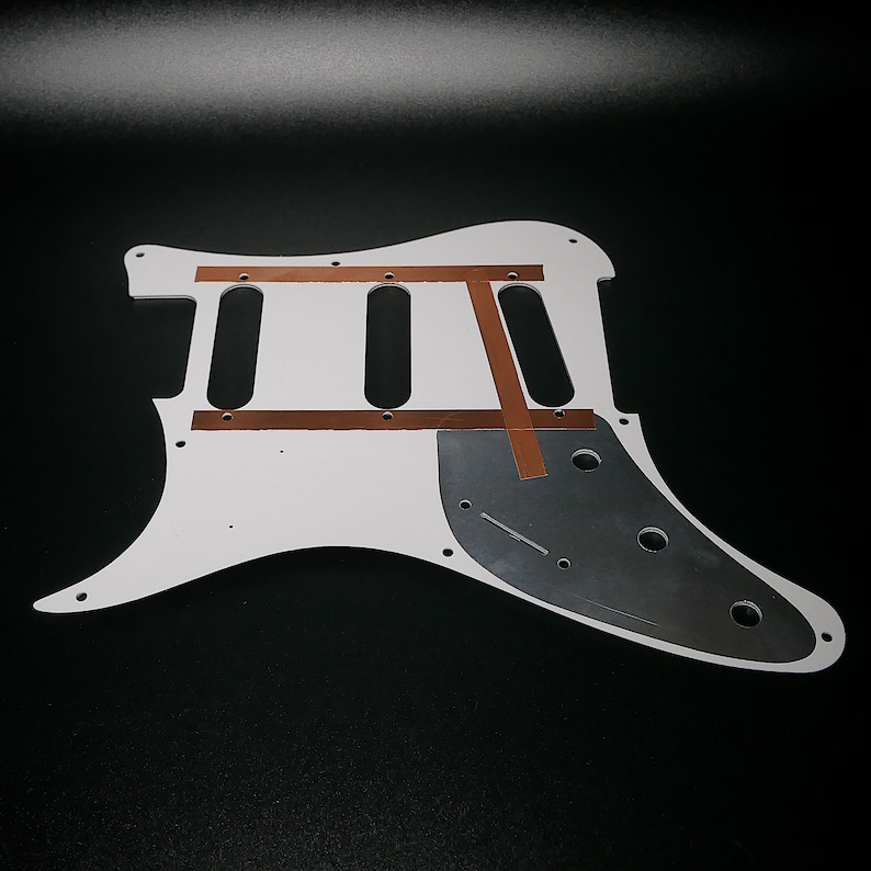 Pu&ograve; includere: Corpo di chitarra elettrica bianco con nastro di rame e un battipenna nero. Il corpo &egrave; in legno e ha una forma classica.