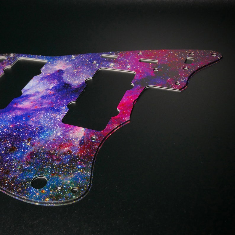 Op de afbeelding: Een gitaar pickguard met een galaxy-thema met een paars, blauw en roze nevelontwerp. De pickguard is gemaakt van helder plastic en heeft een glinsterende afwerking.