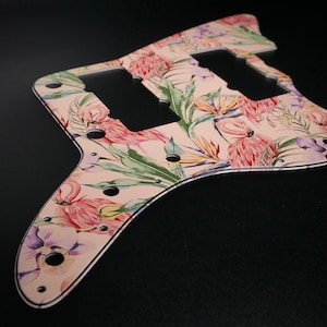 May include: A pink and green guitar pickguard with a tropical floral design featuring flamingos and palm leaves.