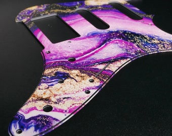 May include: A purple, white, and gold guitar pickguard with a marbled design. The pickguard is made of a clear plastic material and has a glossy finish.