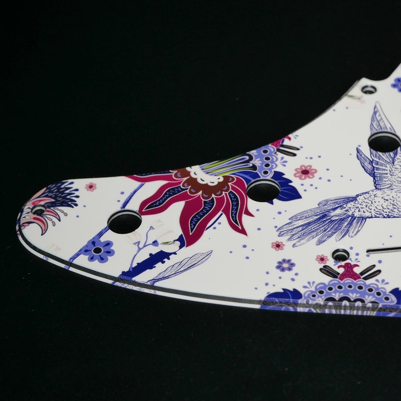 Pu&ograve; includere: Battuta per chitarra bianca con un design floreale e un colibr&igrave; in tonalit&agrave; di blu, viola e rosa.