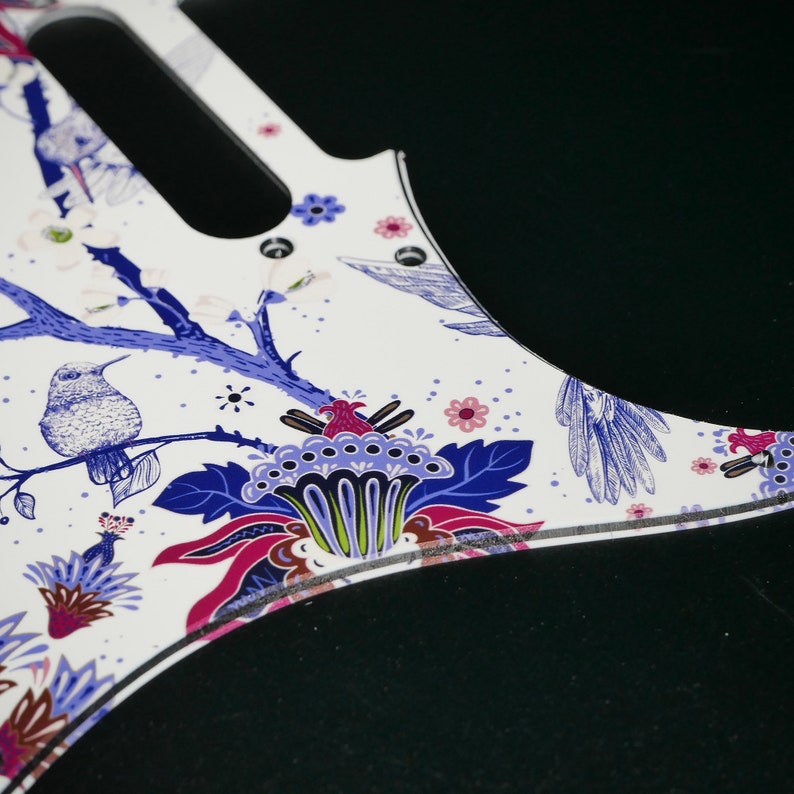 Pu&ograve; includere: Battuta di chitarra bianca con un design floreale blu e rosa con uccelli e fiori.