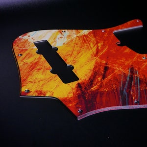 May include: A red, orange, and yellow abstract guitar pickguard with a black pickup cutout.