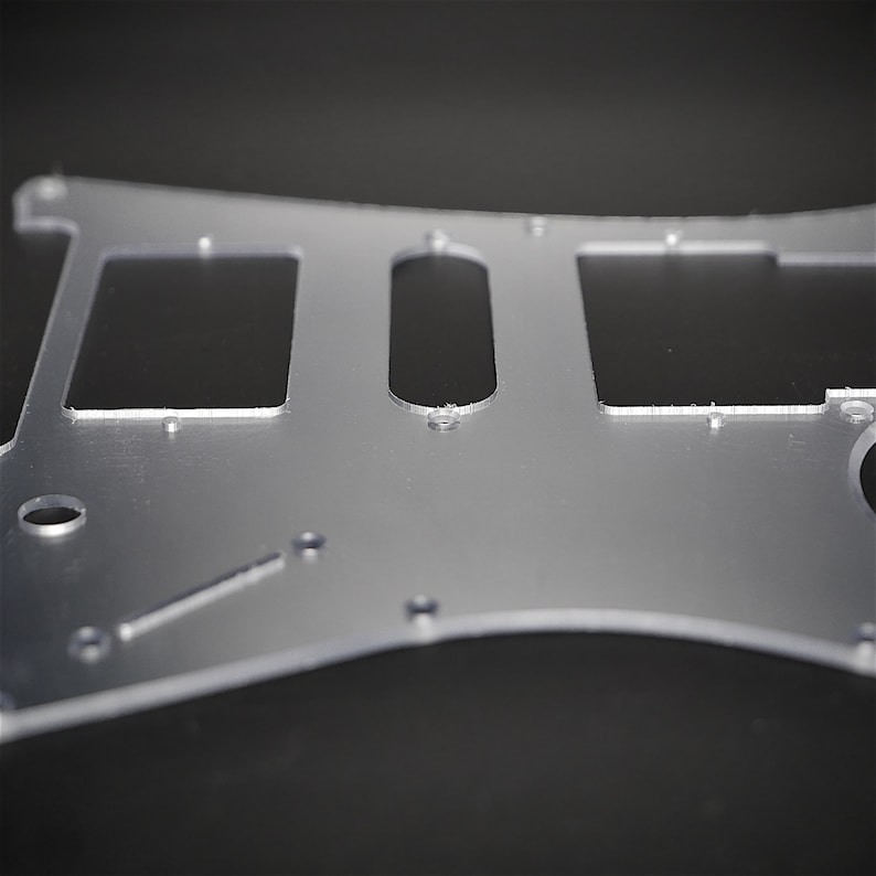 May include: A clear plastic guitar pickguard with cutouts for pickups and controls.