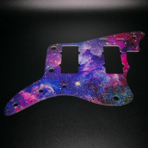 Op de afbeelding: Een gitaar pickguard met een galaxy print in tinten van paars, roze en blauw met een strooiing van zilveren glitter.