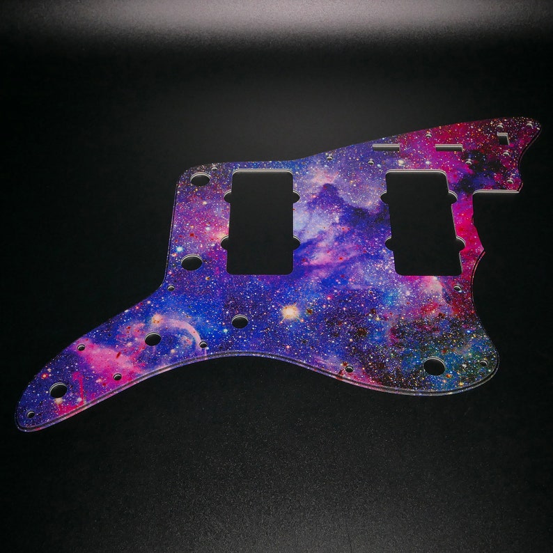 Op de afbeelding: Een gitaar pickguard met een galaxy print in tinten van paars, roze en blauw met een strooiing van zilveren glitter.