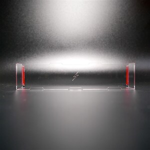Könnte beinhalten: Ein durchsichtiger Acryl-Präsentationsständer mit roten Akzenten. Der Ständer hat ein Blitz-Design in der Mitte.
